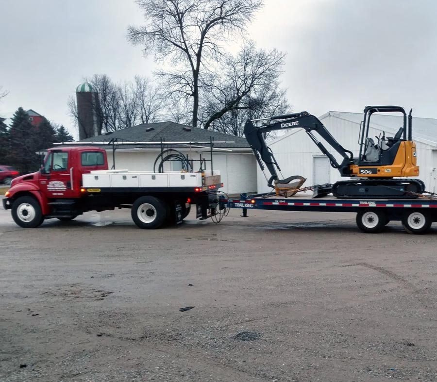 Johnson Well Drilling truck hauling excavator